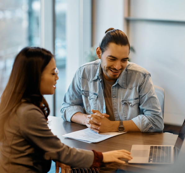 talking-person Zwei Personen am Tisch schauen auf einen Laptop und besprechen Dokumente im modernen Büro.